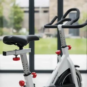 Detail view of the ergonomic adjustable padded saddle and multi-grip handlebars for a comfortable home cycling experience.