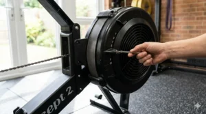 A close-up of a hand adjusting the damper lever on an air rower flywheel to change resistance levels for a CrossFit session.