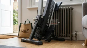 A detailed close-up illustration of the FOLDFAST MAGNETIC rower's compact folding mechanism, revealing precise 18cm depth measurements against a vintage radiator in a small UK flat.