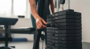 Hand adjusting the weight stack selector pin on a durable single stack multi gym.