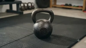 Close-up of a single cast iron kettlebell resting on a wooden floor in a home workout space.